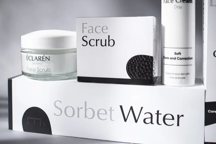 Éclarén: Face Scrub and Sorbet Water cartons up close, the scrub’s black smear carrying a raised, bubbled varnish