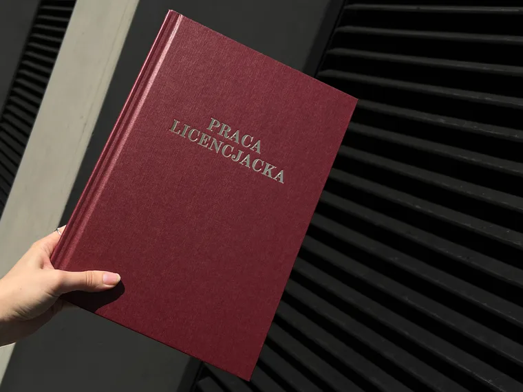 The bound bachelor thesis, Praca licencjacka, held up in sunlight